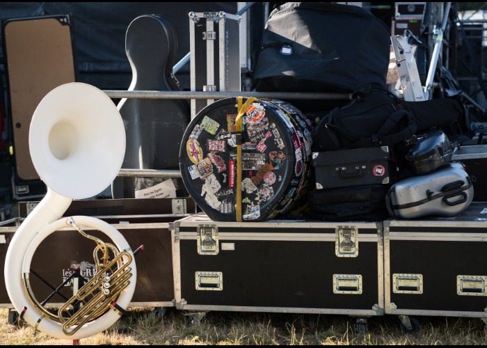 French horn standing backstage next to band equipment cases.