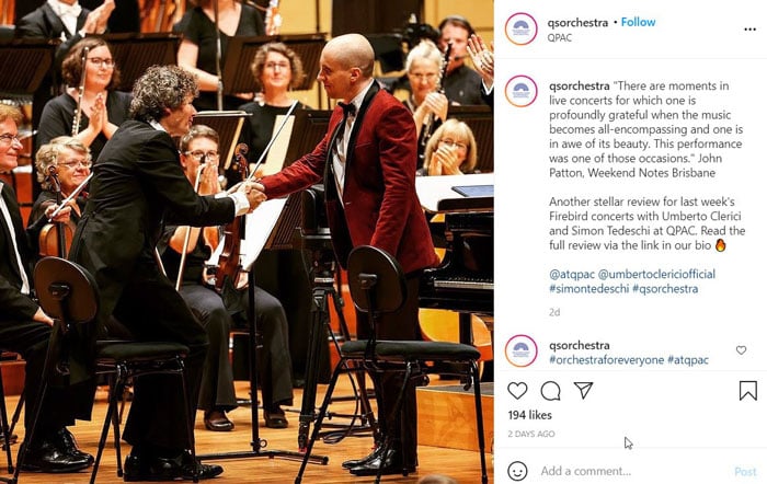 Screenshot of an Instagram post by @qsorchestra, showing a pianist in a dark red tuxedo jacket shaking the hand of the concertmaster. 