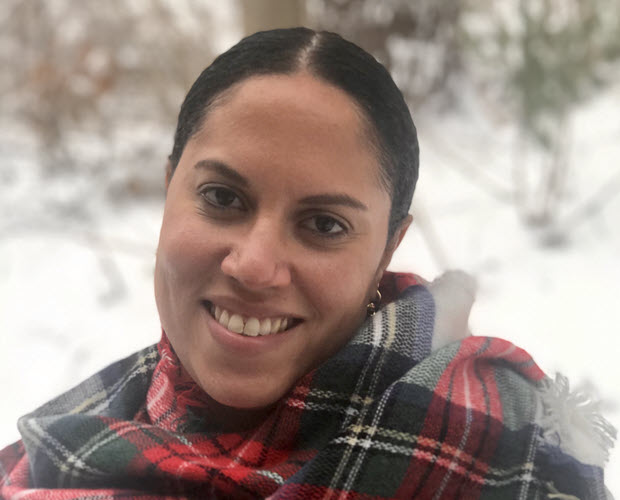 Zorelly Cepeda Derieux, a Latinx woman with dark hair pulled back and wearing a plaid scarf, seen outside.