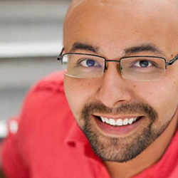 Greg Garcia, a man with a goatee wearing glasses and a red shirt