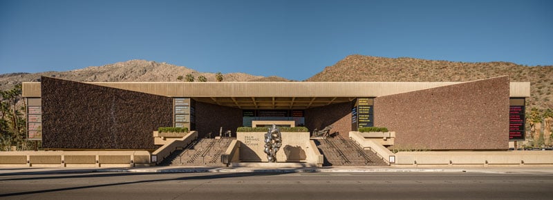 A building in Desert Modern style with mountains behind and blue sky above