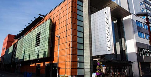 A modern-looking building with a variety of construction materials, and a silvery panel with large letters spelling "Hippodrome". Blue sky overhead.