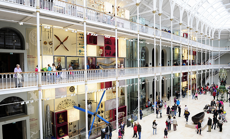 Interior image of visitors in the open, multilevel grand gallery of the National Museum of Scotland