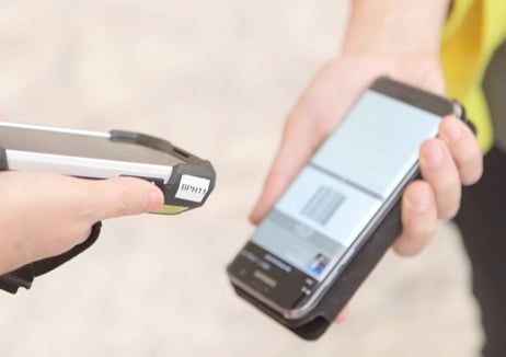 A scanner pointed at a mobile phone showing a ticket barcode