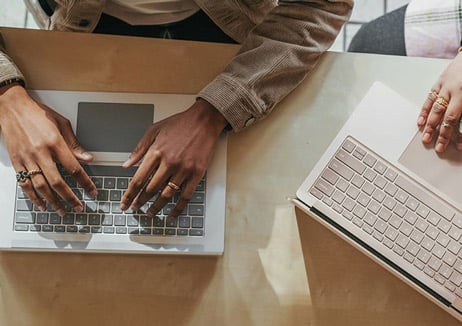 People's hands on laptops viewed from above