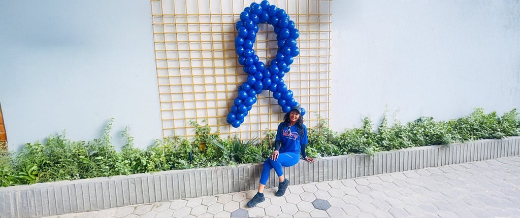 Aline Kidd cancer patient photo outside sitting on a concrete.