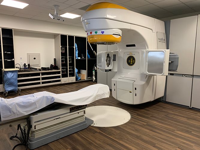 Front view of a Varian TrueBeam linear accelerator showing the gantry head, onboard imaging arms, and electronic portal imaging device