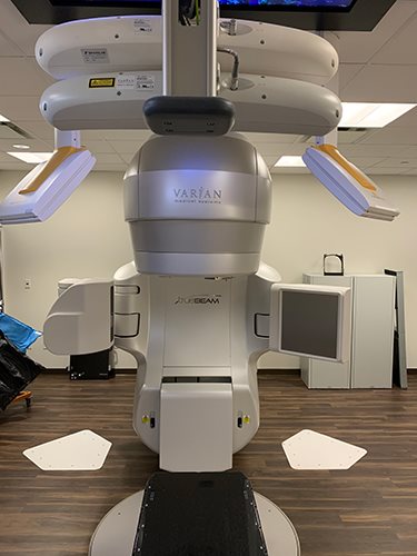 Varian linear accelerator with decorative cream and yellow gantry cover featuring heart accents, configured for pediatric-friendly radiation therapy treatments