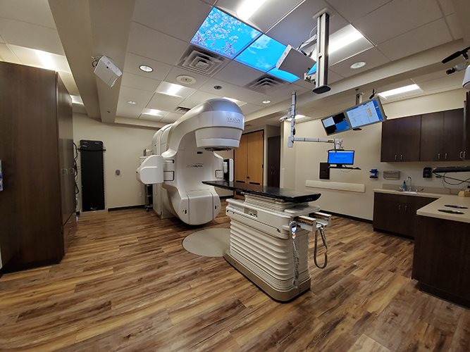 GE LightSpeed CT scanner with patient couch and green footprint floor markers indicating patient positioning guidance in a simulation suite