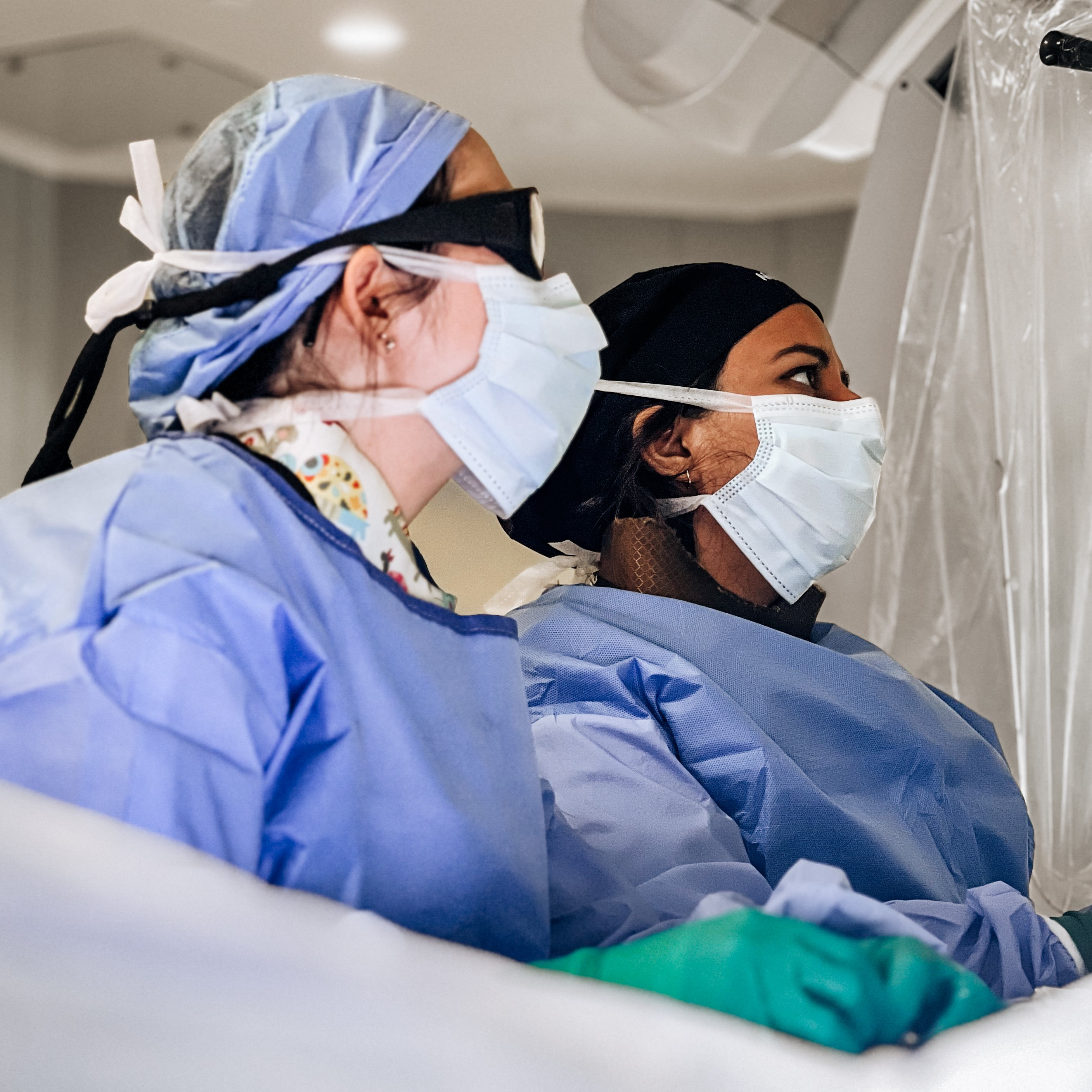 Two residents looking up at a screen during surgery.