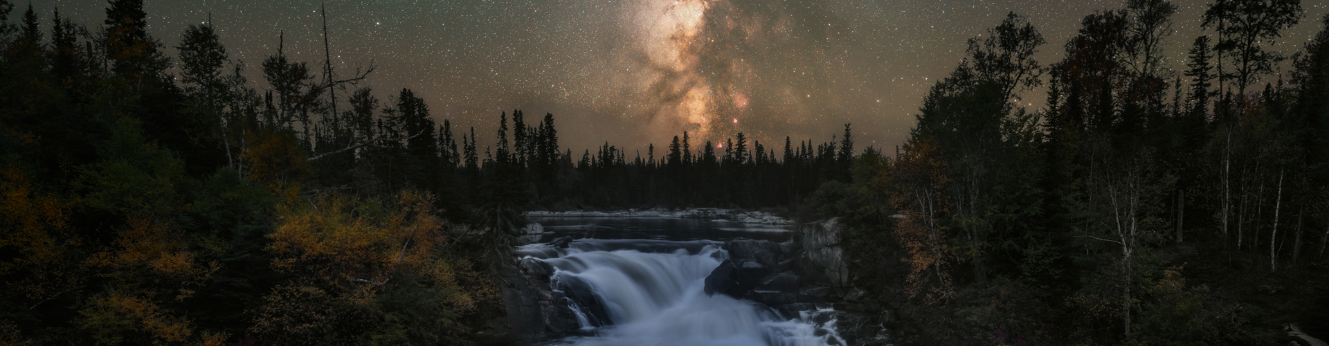 Waterfall at night with the northern lights above.