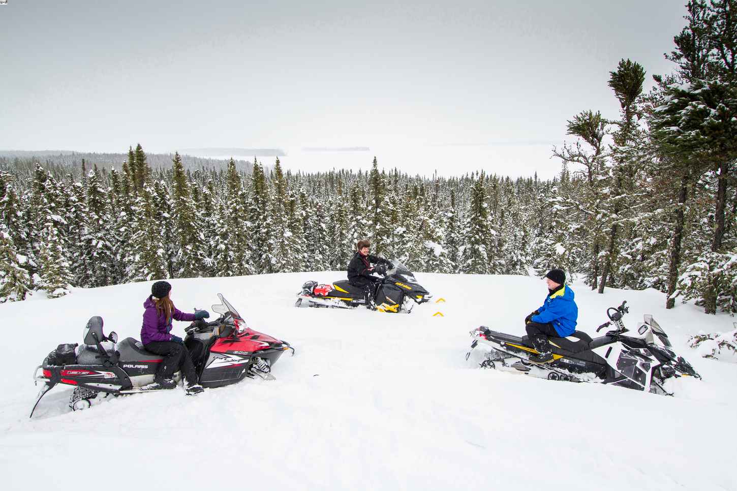 Three people on snowmobiles at Lac LaRonge Provincial Park in Saskatchewan