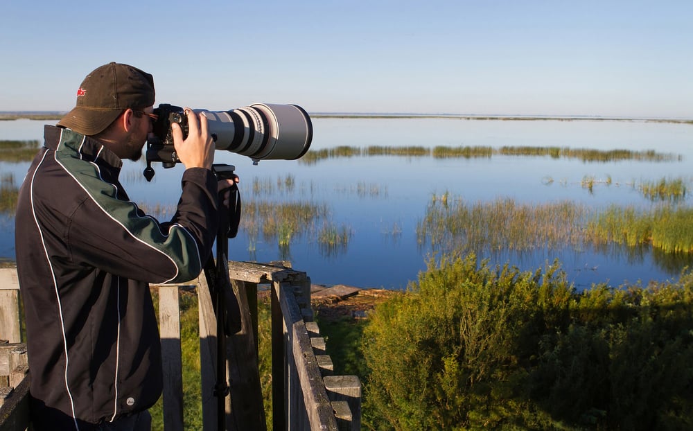 Man with long-lensed camera looking for birds at Quill Lake, Saskatchewan