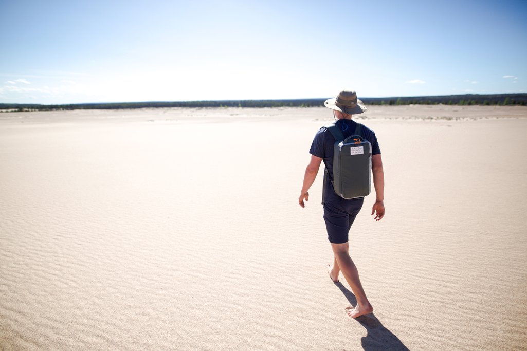 person walking along sand dunes in bare feet.