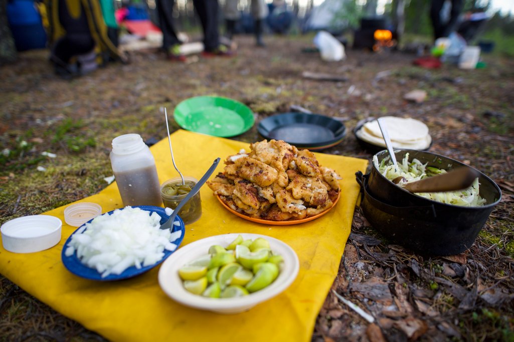 photo of camping food in plates on a mat on the ground