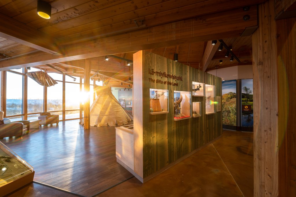 View inside Wanuskewin Heritage Park building with artifacts on display and a tipi in the back.