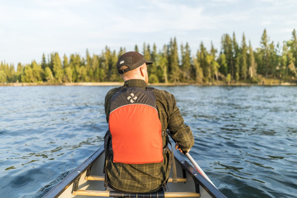 view from inside a canoe looking at another person inside the same canoe paddling on a lake