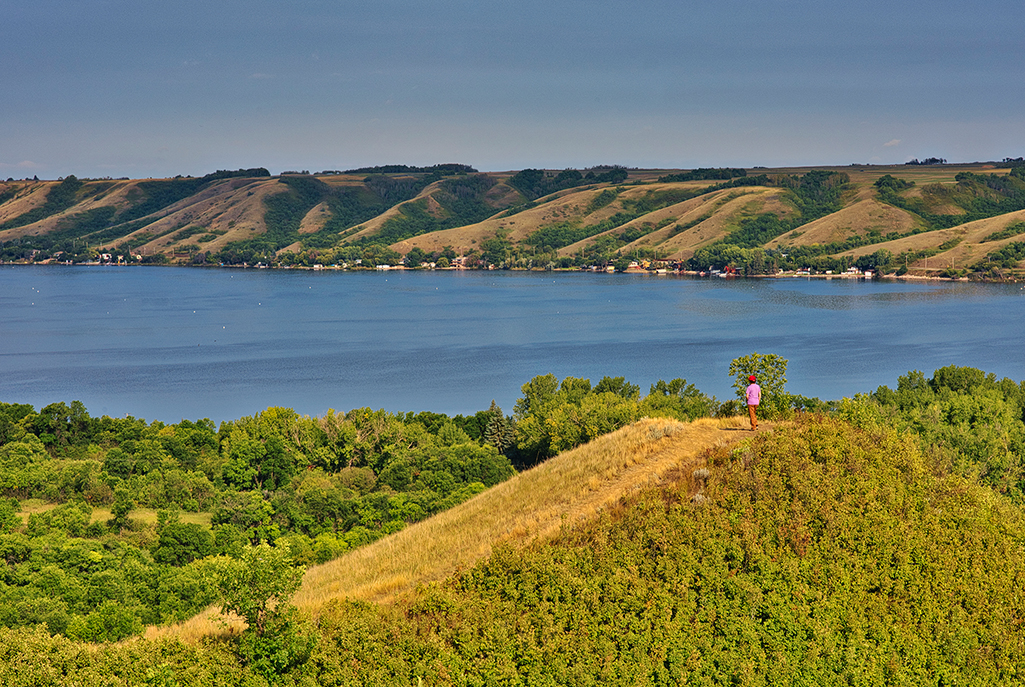 Person standing on hill looking out at lake in Qu'Appelle Valley