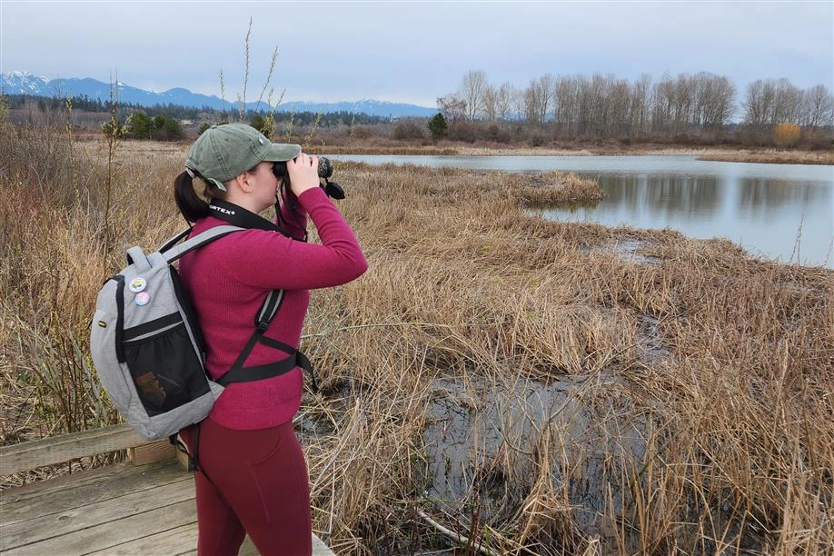 Shayna Cossette looking through binoculars on a birding tour.