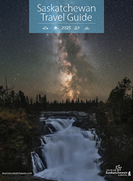 Cover of the 2025 Saskatchewan Travel Guide. A waterfall at night with the Milky Way in the sky.