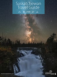 Cover of the 2025 Saskatchewan Travel Guide. A waterfall at night with the Milky Way in the sky.