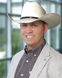Headshot of Shaun Kindopp. He is wearing a cream coloured Stetson hat, a dark grey button up shirt and light grey sports jacket.