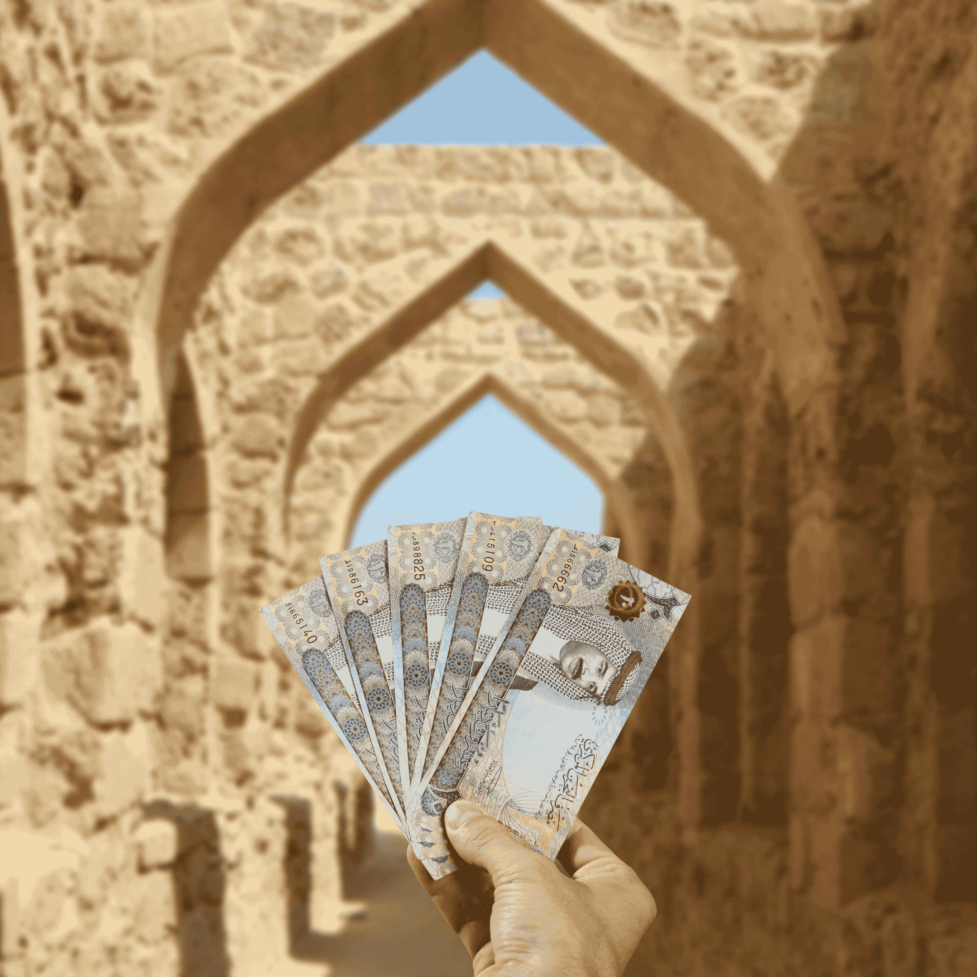 Traveller holding Bahraini Dinar (BHD) in front of Qal’at al-Bahrain (Bahrain Fort)
