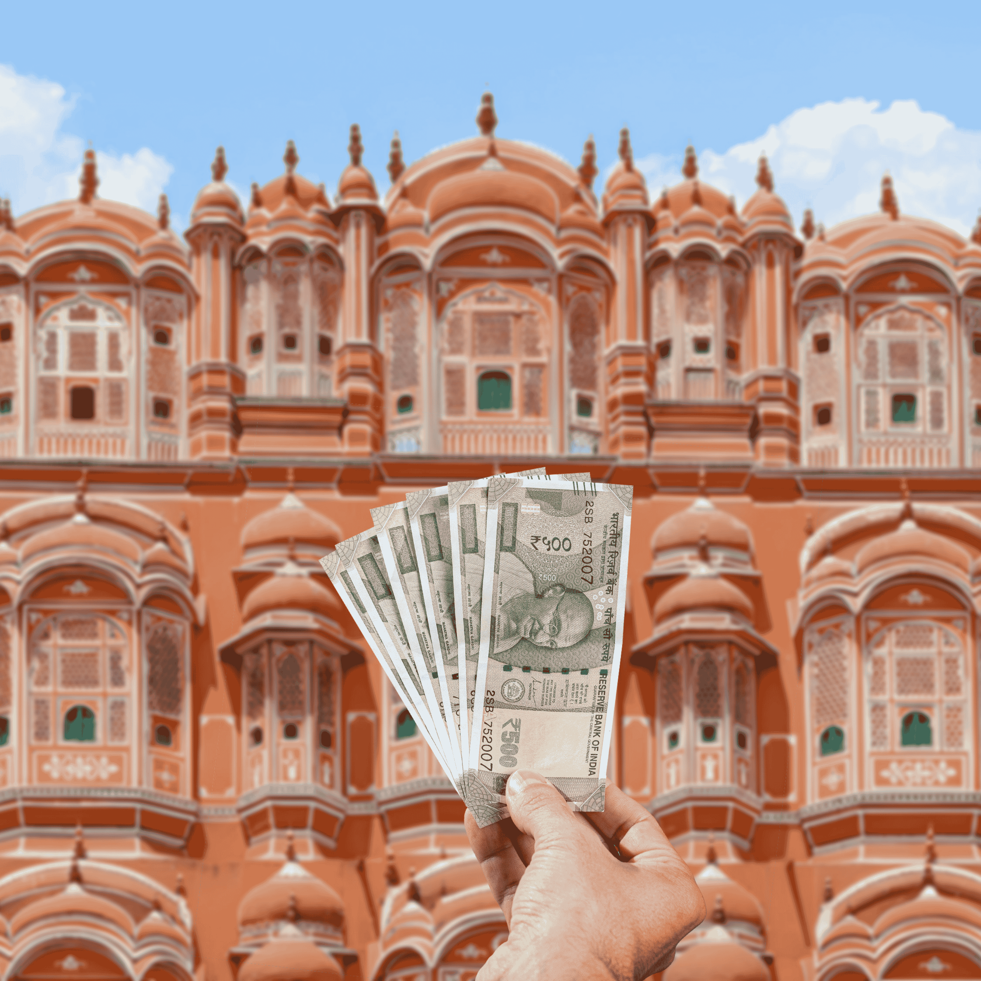 Traveller holding Indian Rupees (INR) currency in front of Pink Palace in Jaipur, India