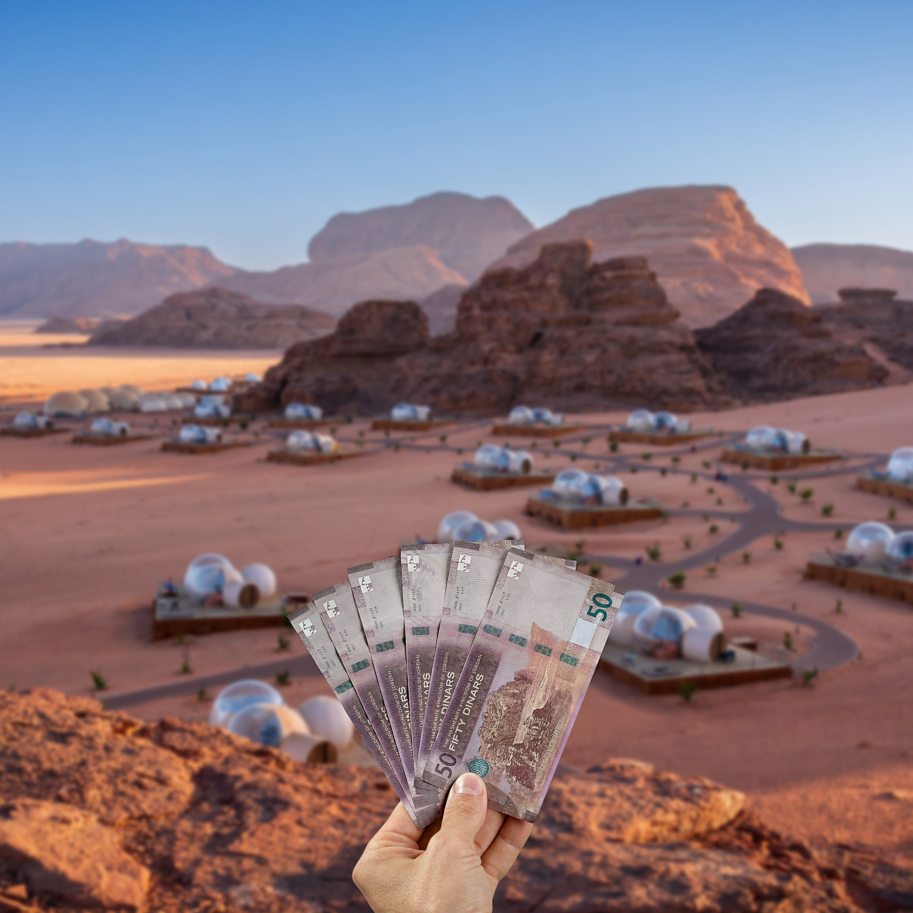 Traveller holding Jordanian Dinar (JOD) currency in front view of Wadi Rum, Jordan