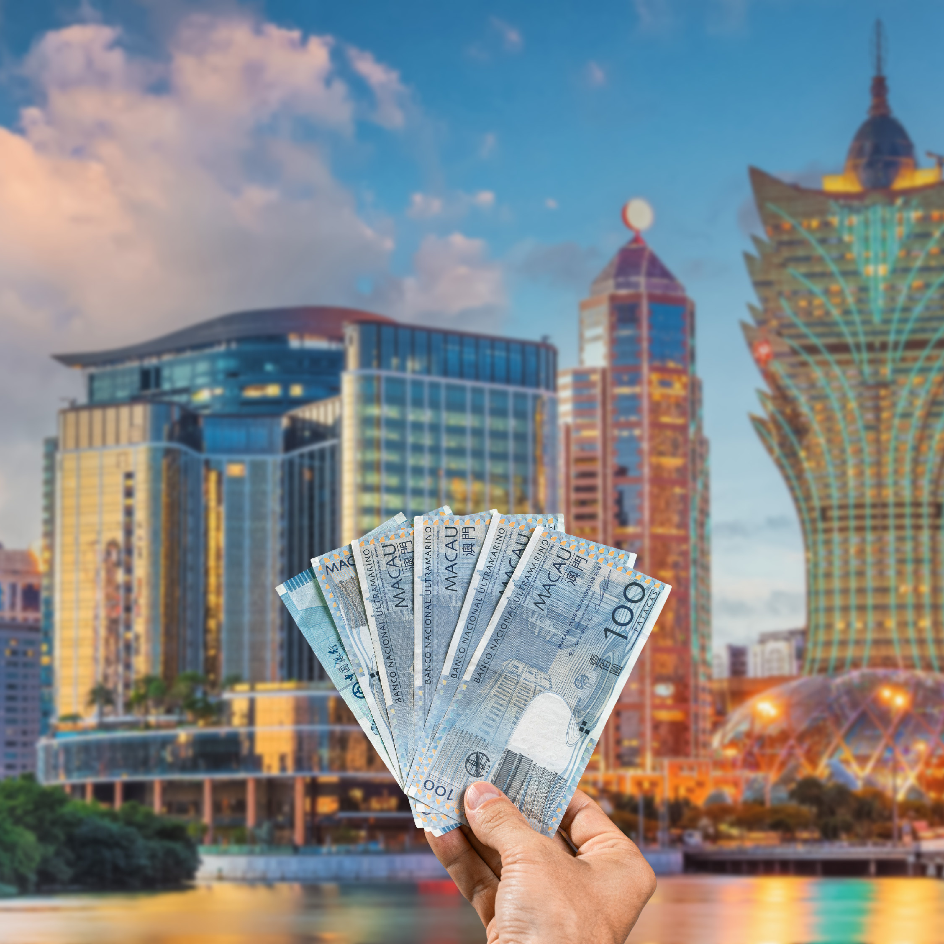 Traveller holding Macanese Pataca (MOP) currency in front view of Macau skyline, Macau