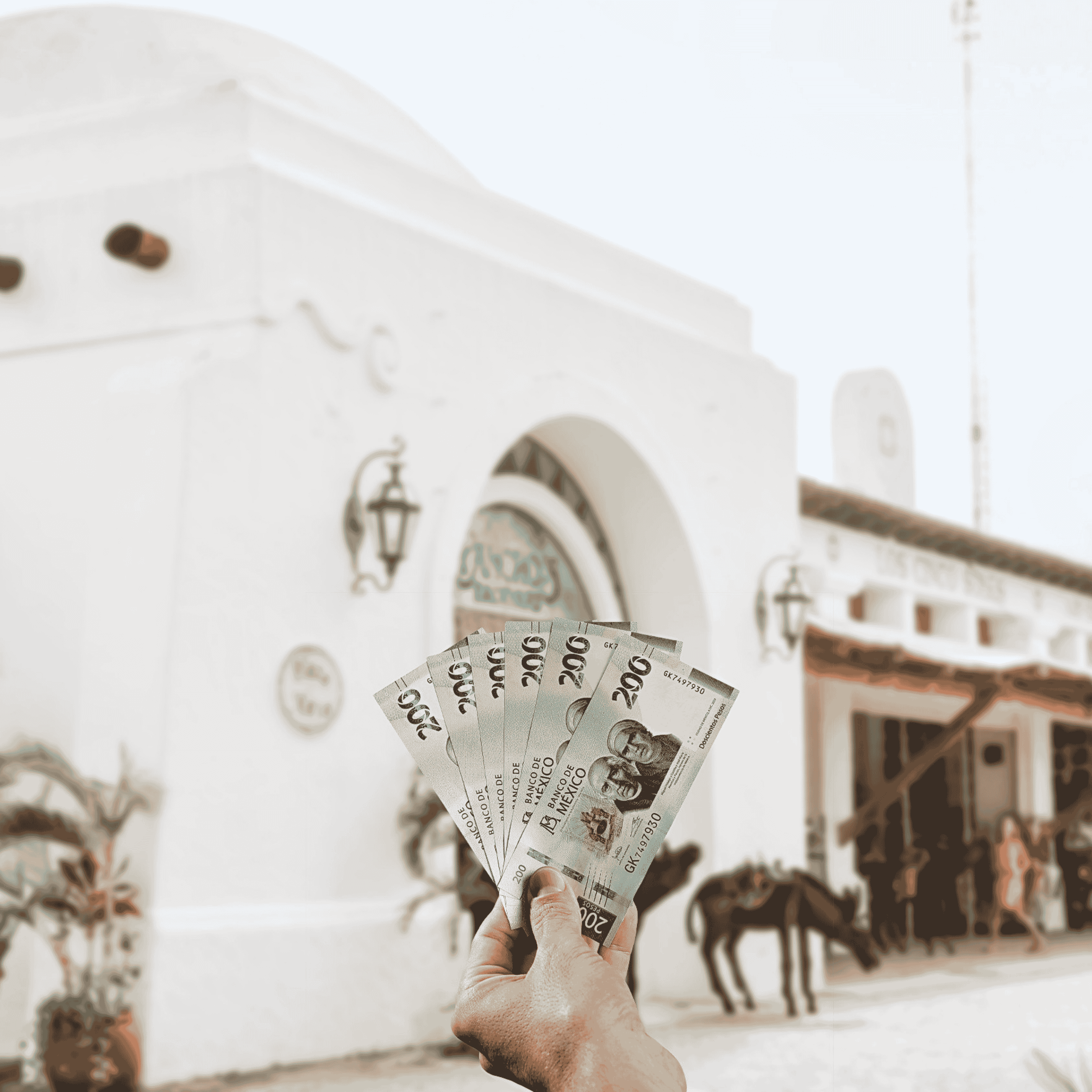 Traveller holding Mexican Pesos (MXN) currency in front of traditional white building with donkeys in the background in Mexico