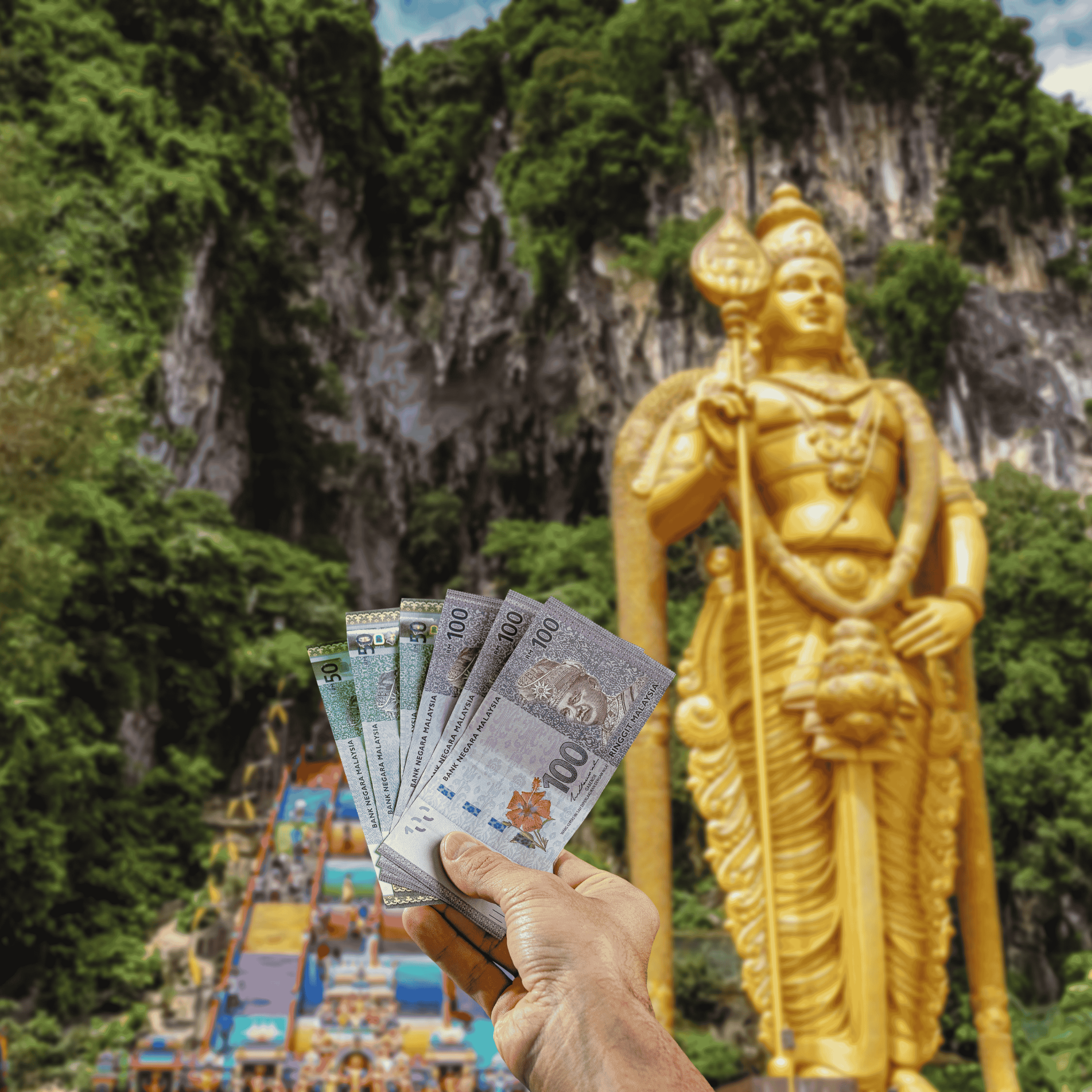 Traveller holding Malaysian Ringgits (MYR) currency in front view of Batu Caves in Malaysia