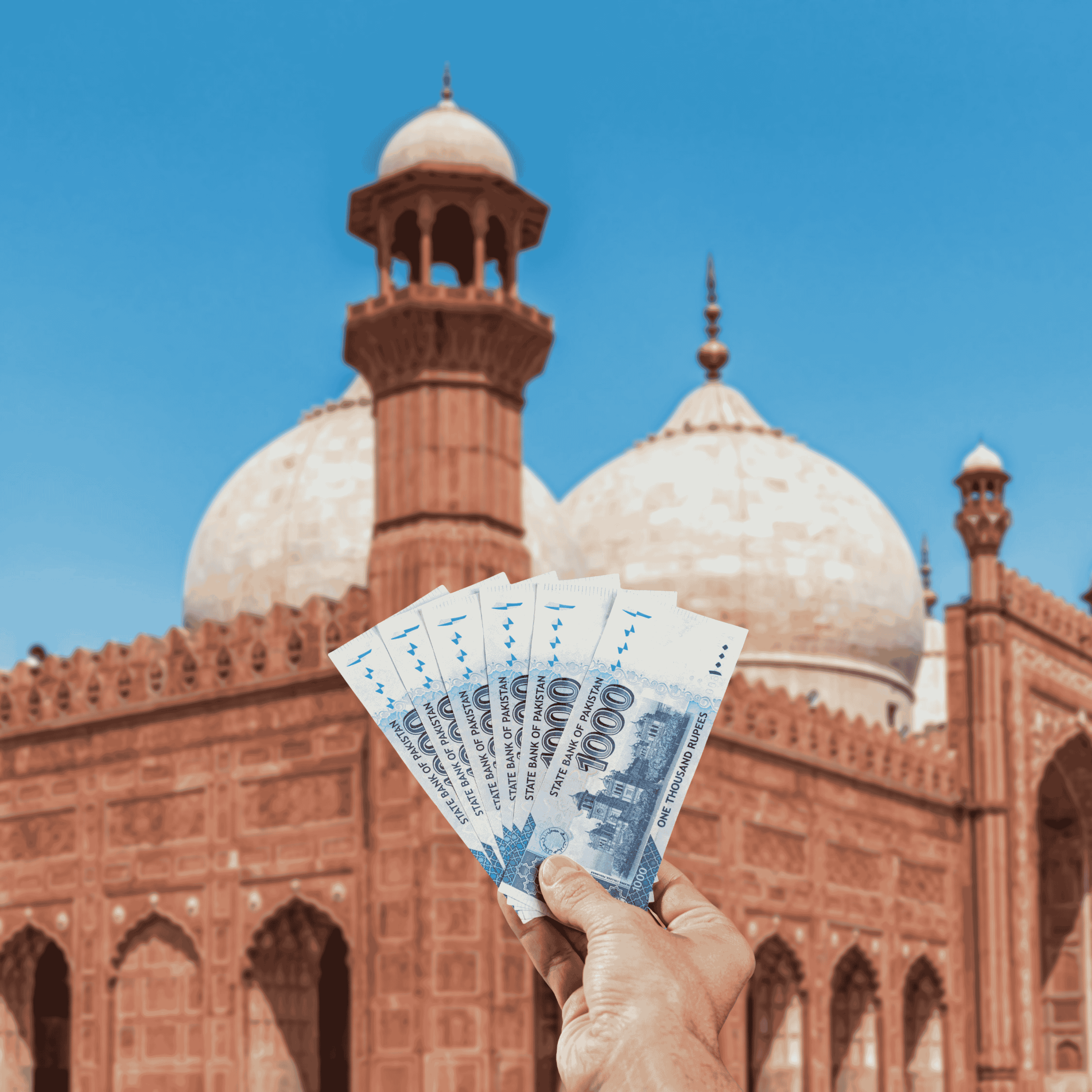 Traveller holding Pakistani Rupees (PKR) currency in front view of Badshahi Mosque, Pakistan