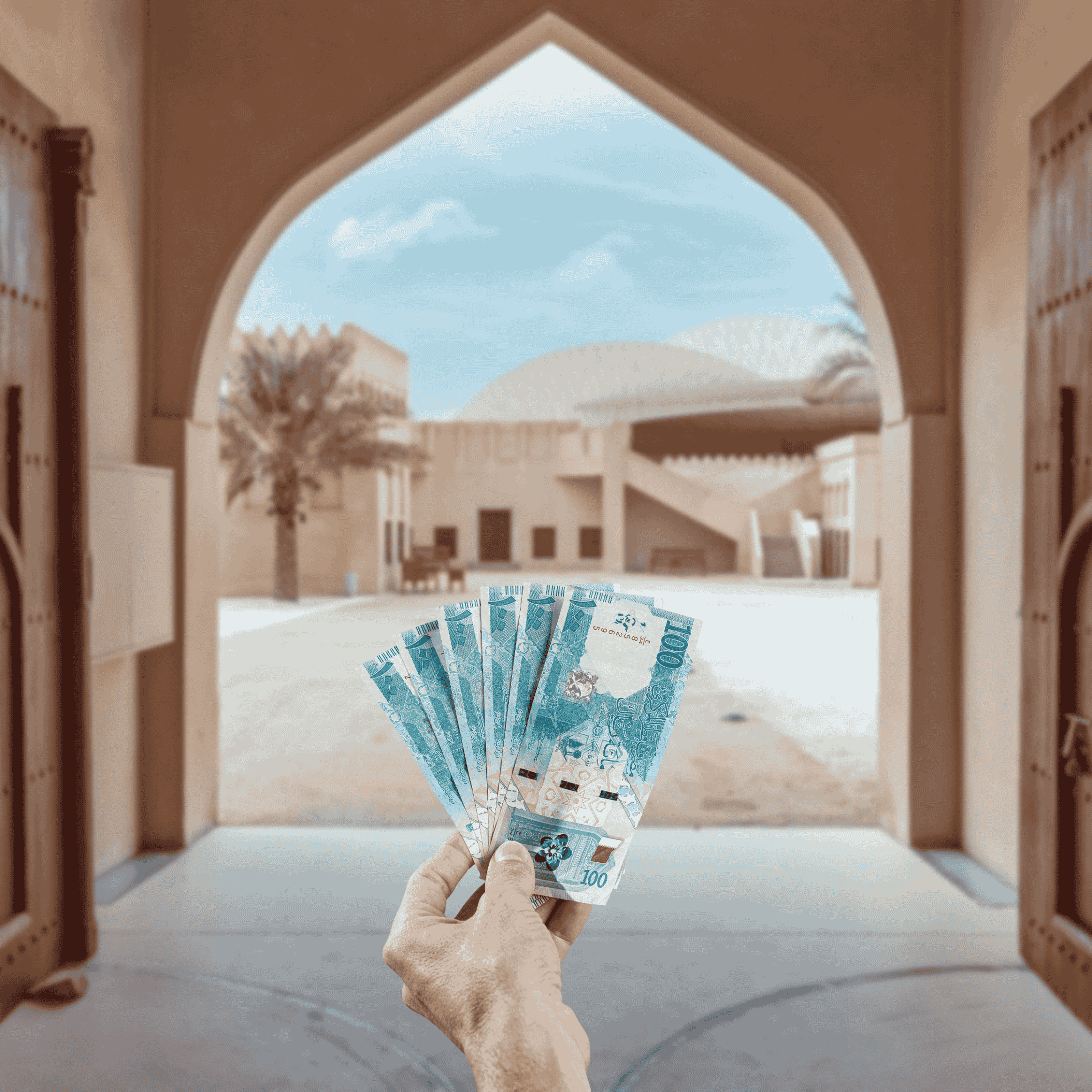 Traveller holding Qatari Riyal (QAR) currency in front view of Sheikh Abdulla bin Jassim Al-Thani palace at the National Museum of Qatar in Doha, Qatar