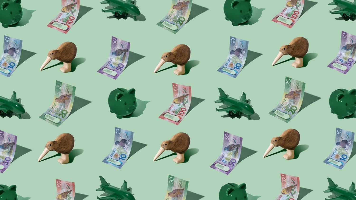 New Zealand Dollar (NZD) currency banknotes laid out in a playful pattern with a green piggybank, green plane, and kiwi figurine for Travel Money Oz.