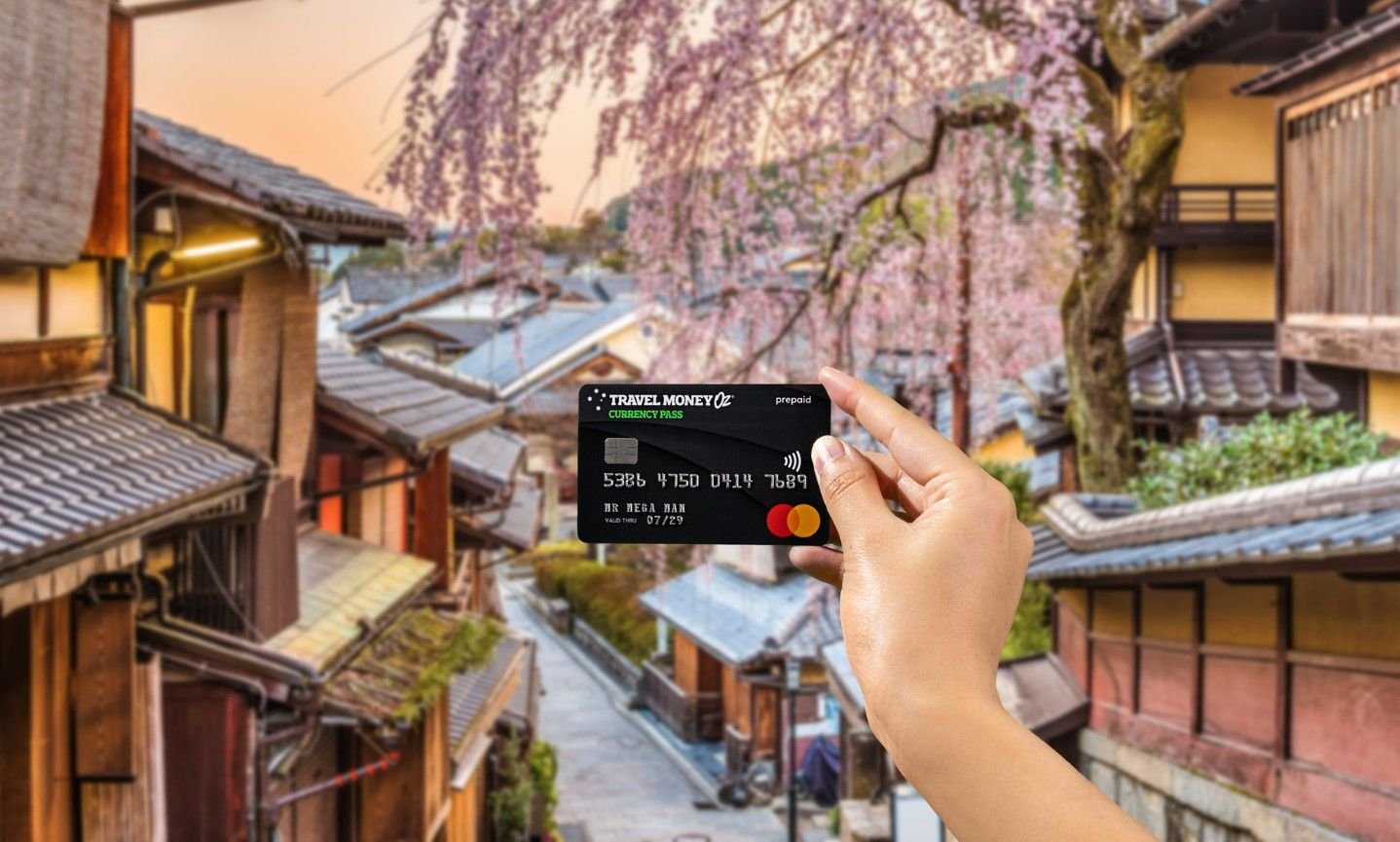 Using Currency Pass travel money card in Japan, featuring cherry blossoms in ancient street in Kyoto