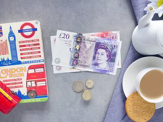 Pound notes, cup of tea and London guide book
