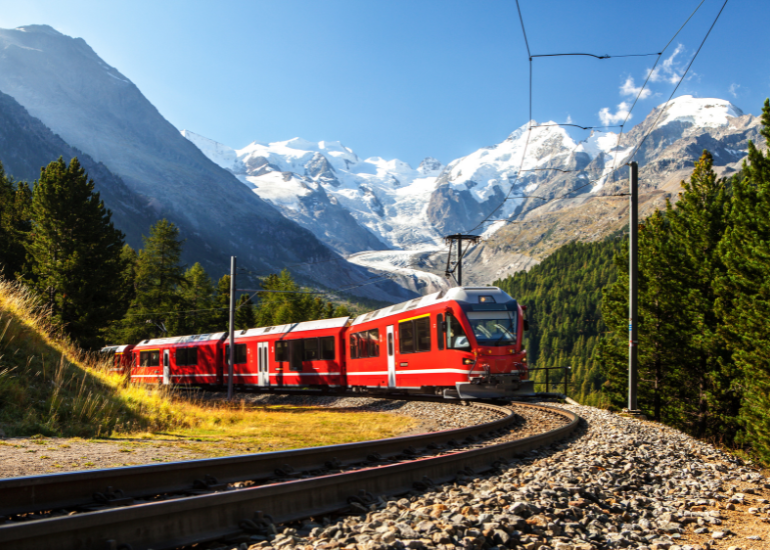 Catching the train across Europe Red train winding through snowcapped alps of Switzerland