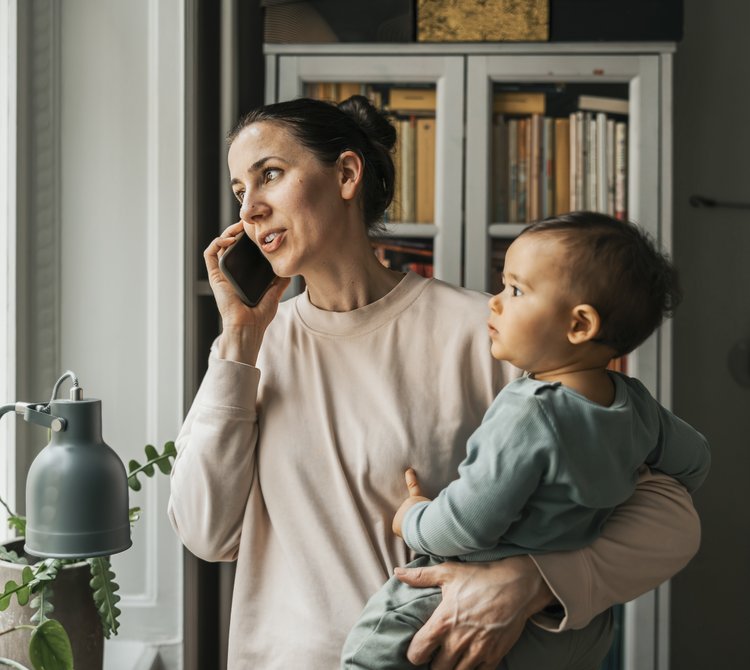 Parent holding a baby while talking on the phone