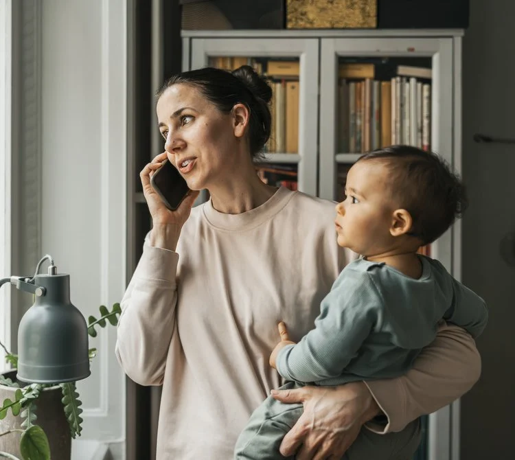 Parent holding a baby while talking on the phone