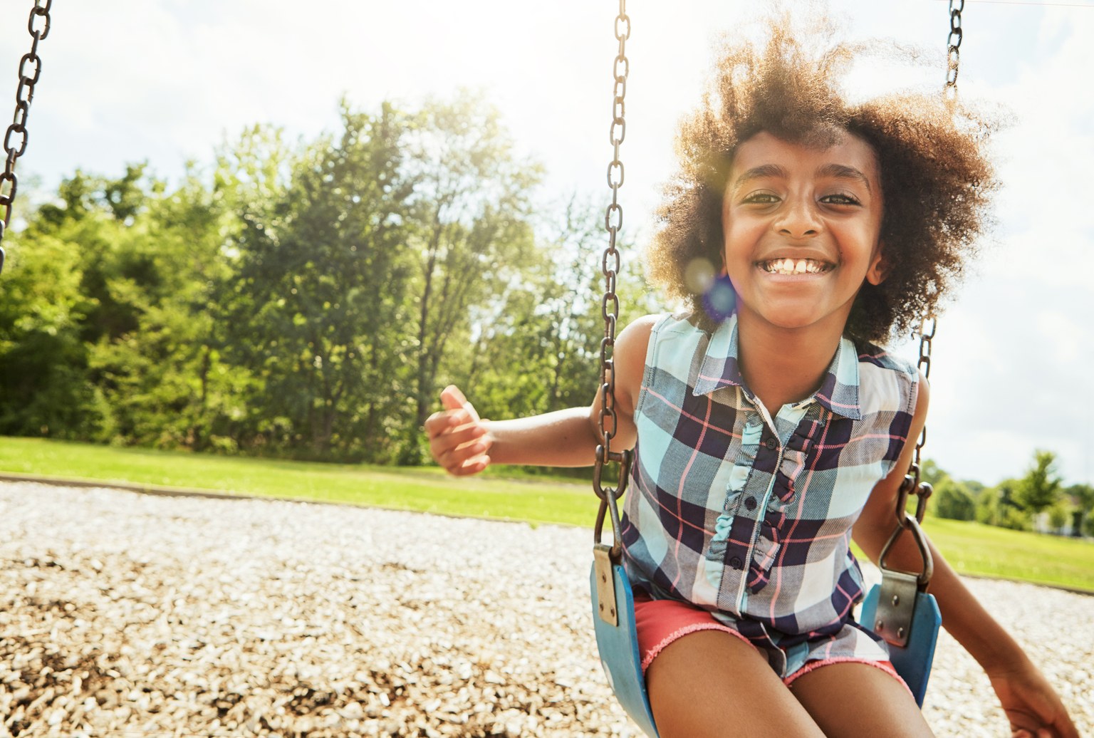 Portrait of a young girl playing on a swing at the park