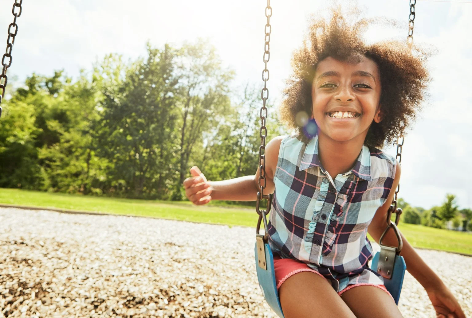 Portrait of a young girl playing on a swing at the park
