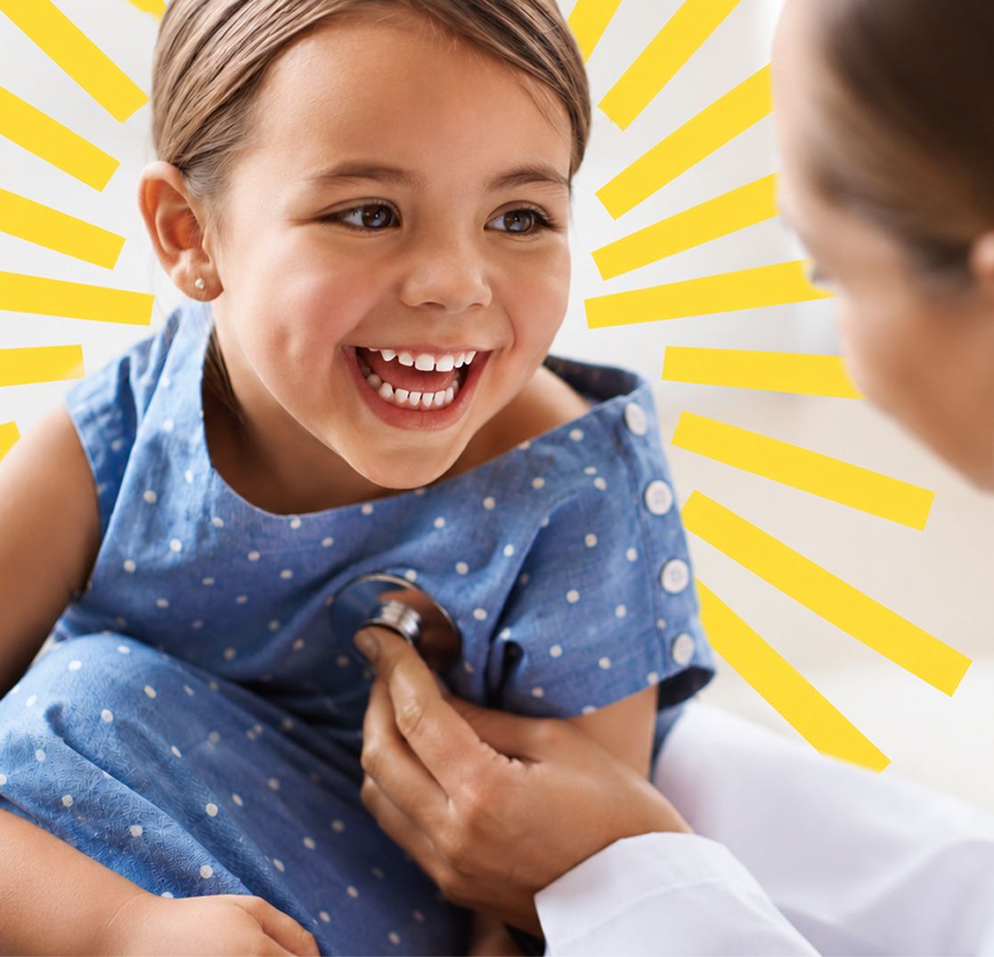 A laughing girl in a blue dress during a checkup with a doctor