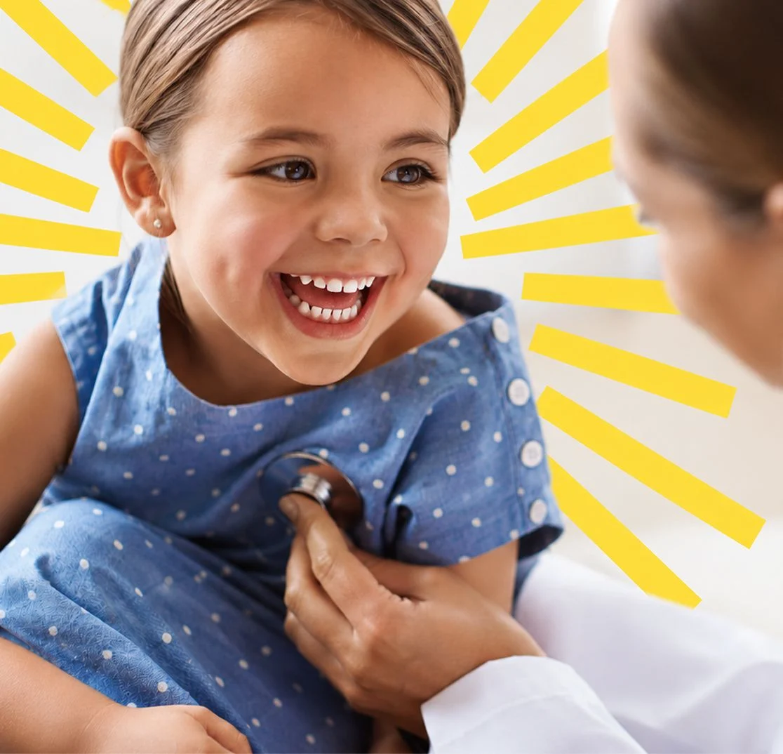 A laughing girl in a blue dress during a checkup with a doctor