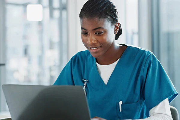 A smiling healthcare professional looking at a laptop screen.