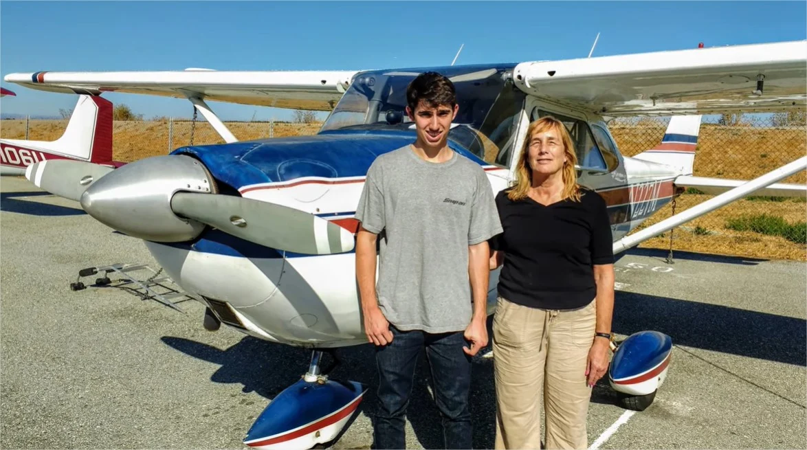 A boy and his mother with an airplane behind them