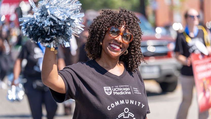 woman in black community tshirt and sunglasses holding silver pompom