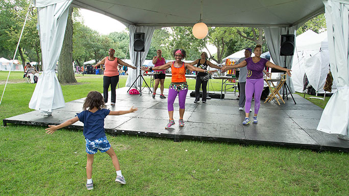 Young girl follows along with a UChicago Medicine zumba class at the African Festival of the Arts in Washington Park