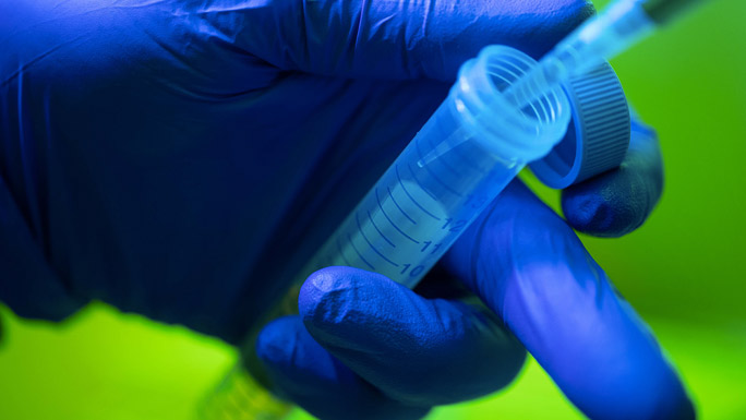 gloved hand with pipette and tube