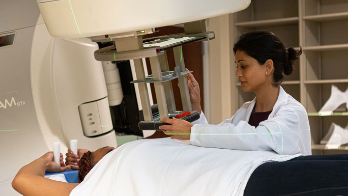 Radiation oncologist Yasmin Hasan, MD, with a patient on the linear accelerator